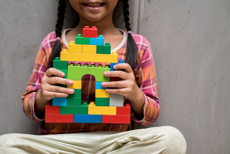 little girl holding lego construction