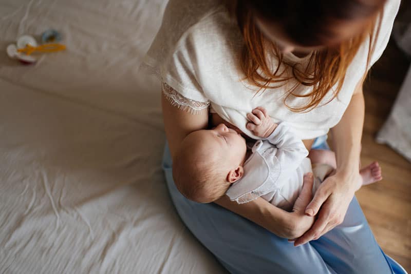 mother breastfeeding baby in bedroom