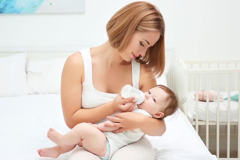 mother feeding baby on the bed