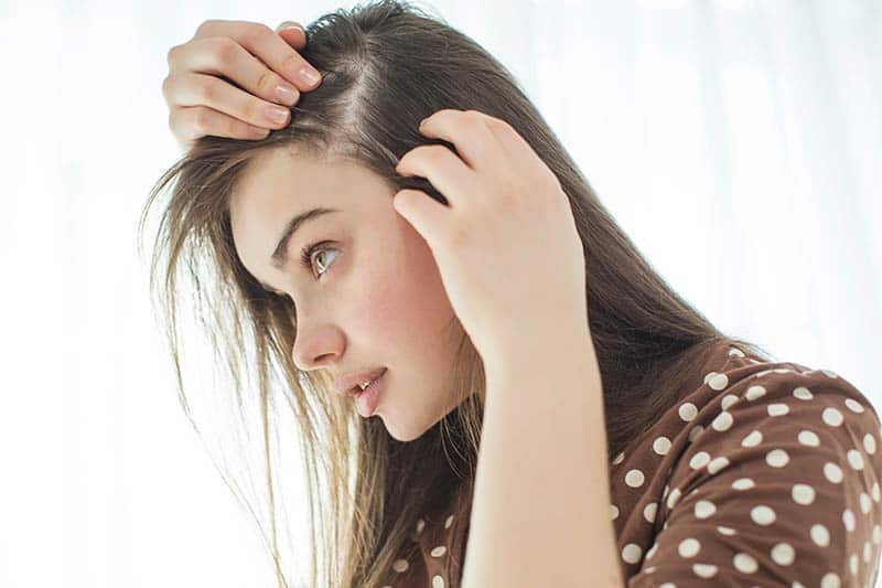 woman checking her hair for hair loss