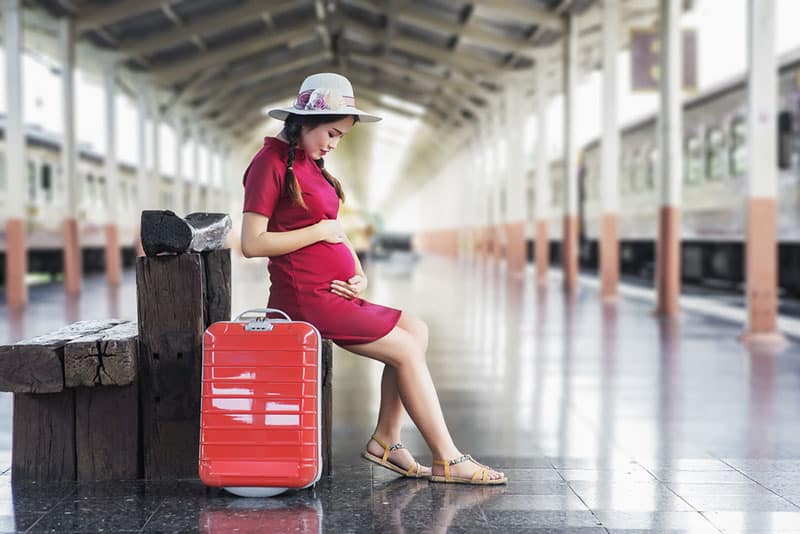 young pregnant woman waiting for train
