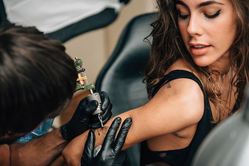 young woman getting new tattoo