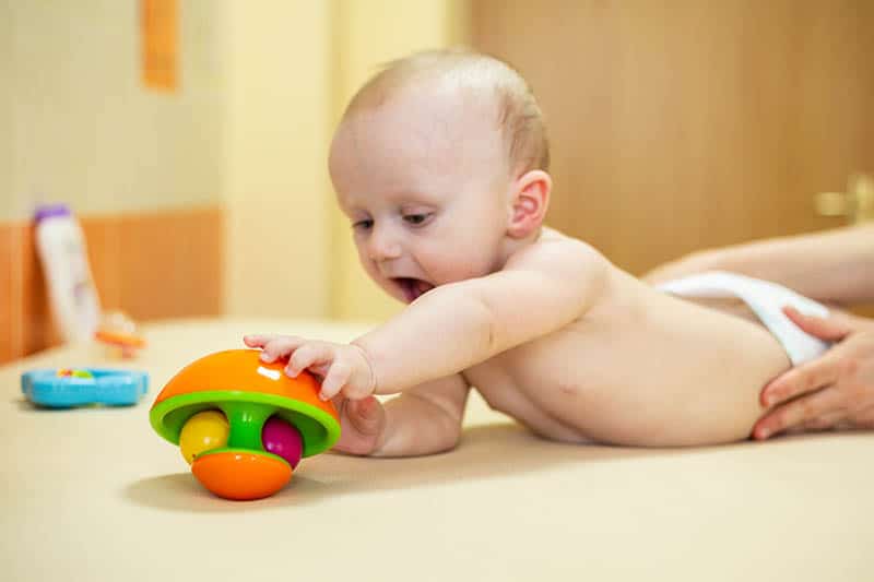baby playing with toy developing gross motor skills