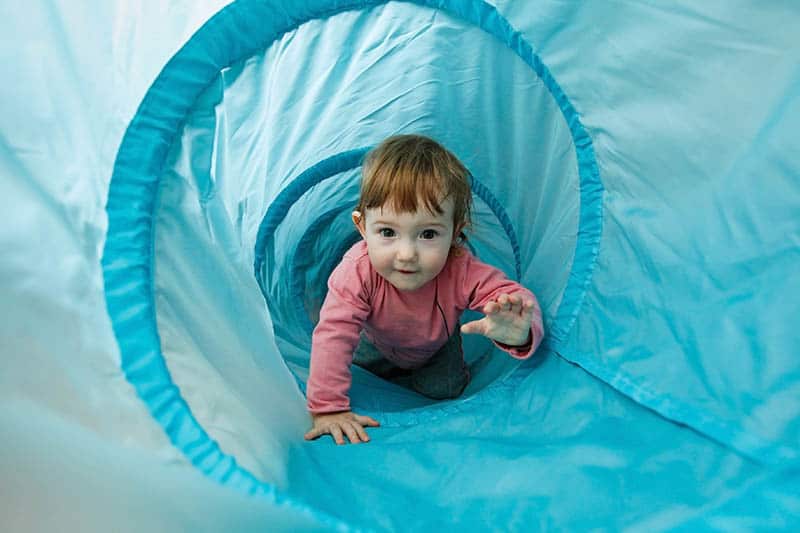 toddler climbing through a tube