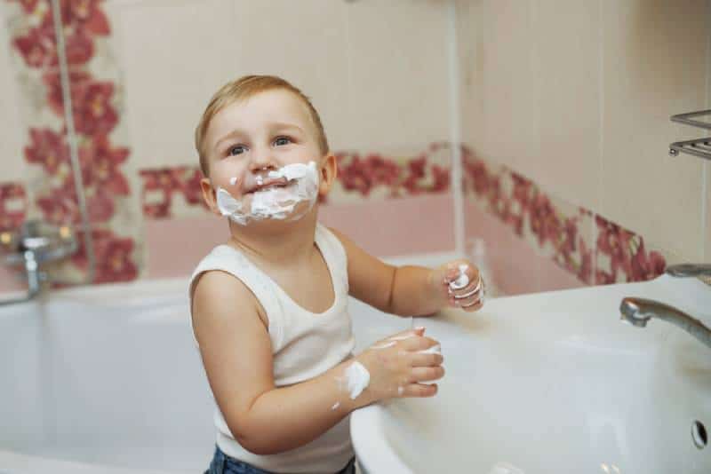 little boy playing with shaving cream in the bathroom