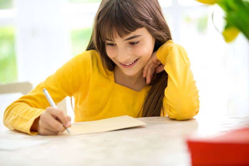 Girl in yellow shirt writing a letter