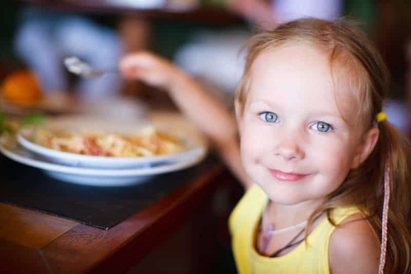 adorable little girl in yellow shirt having lunch