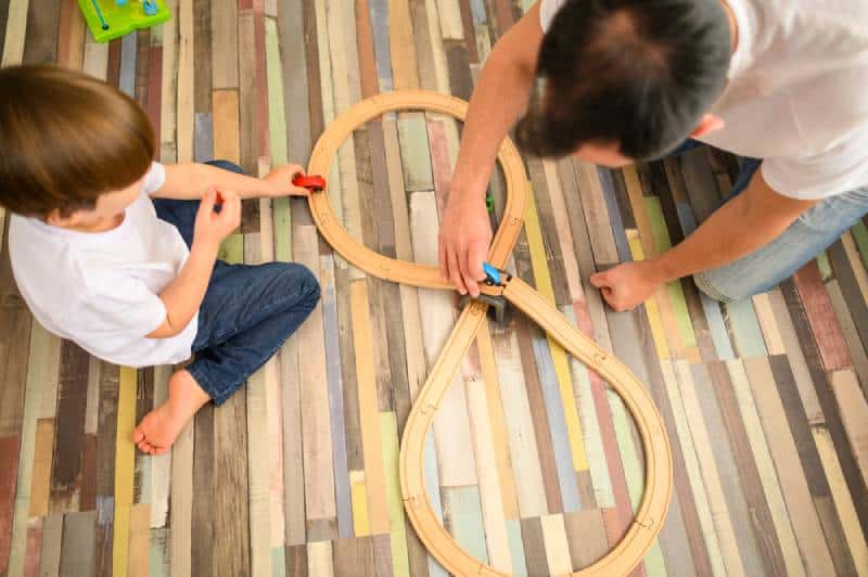 Child and father playing with race track at home