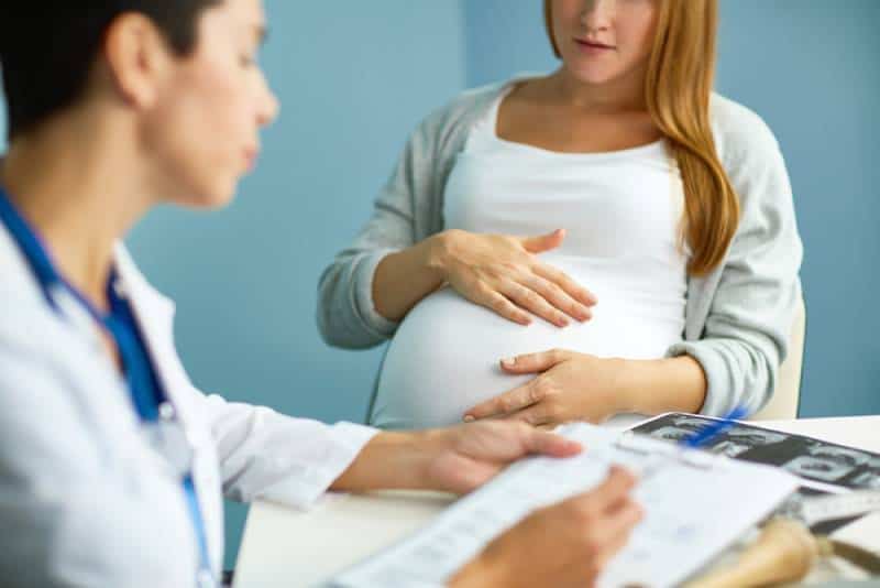 Pregnant Woman visiting obstetrician and holding her belly