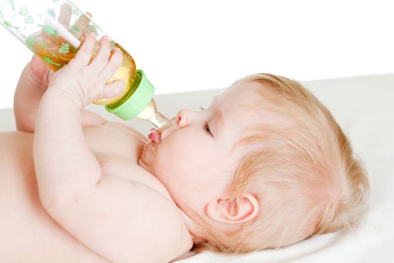 adorable blond child drinking from bottle