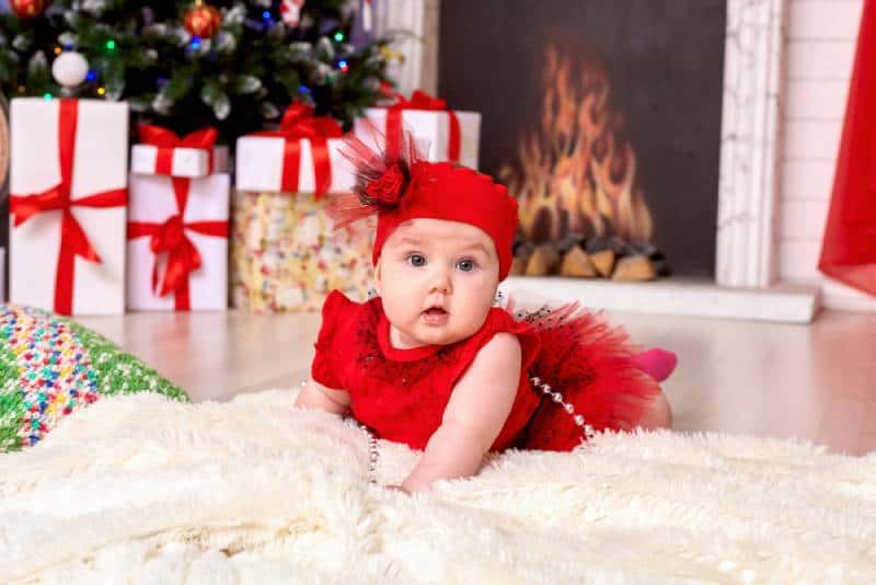 baby child under one year old lies on the background of the Christmas tree and gifts