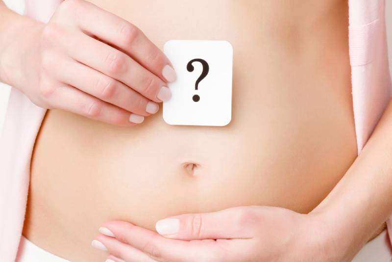 Woman showing question mark on naked belly