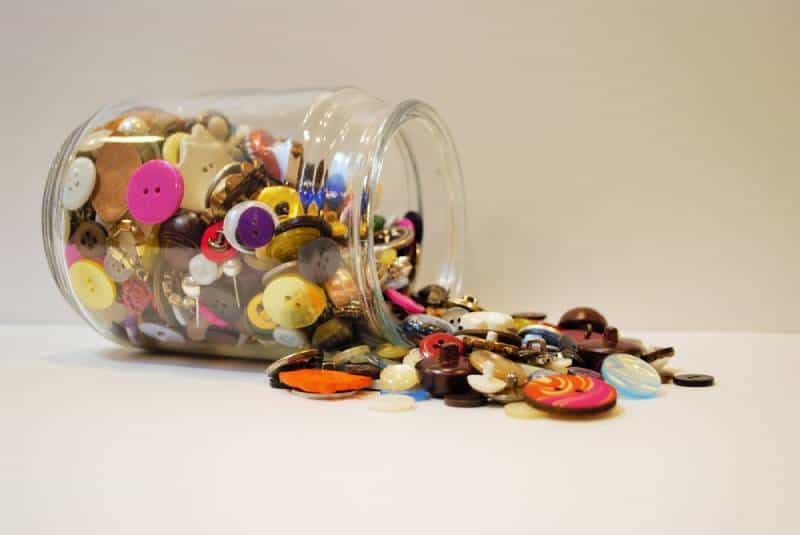 jar full of multi colored buttons overflowing and spilling out