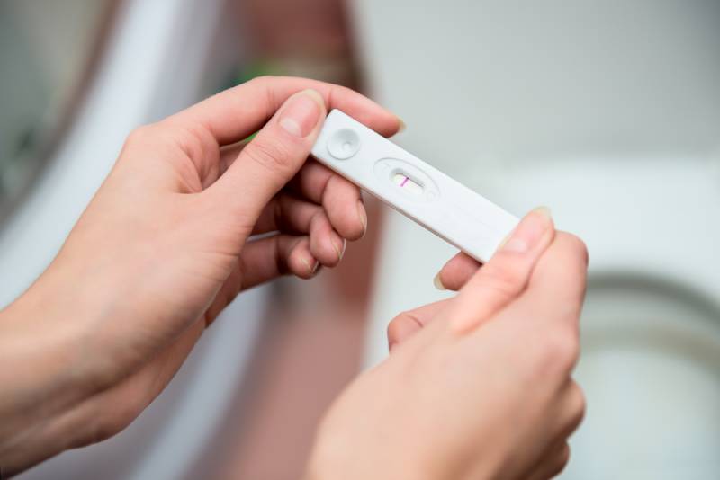 woman holding negative pregnancy test in toilet
