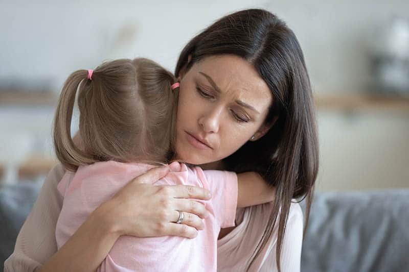 worried single mother hugging daughter 