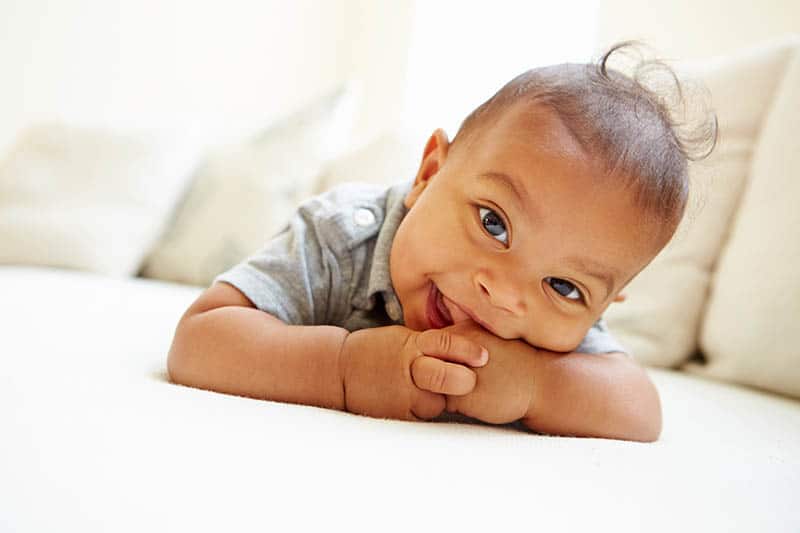 cute baby with unique middle name for boys lying in bed smiling 