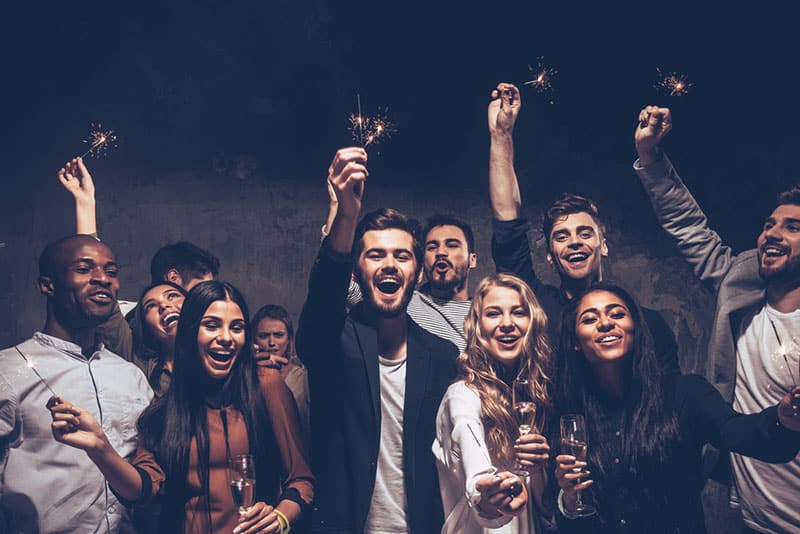 a group of happy friends celebrating a new year in the club with sparklers