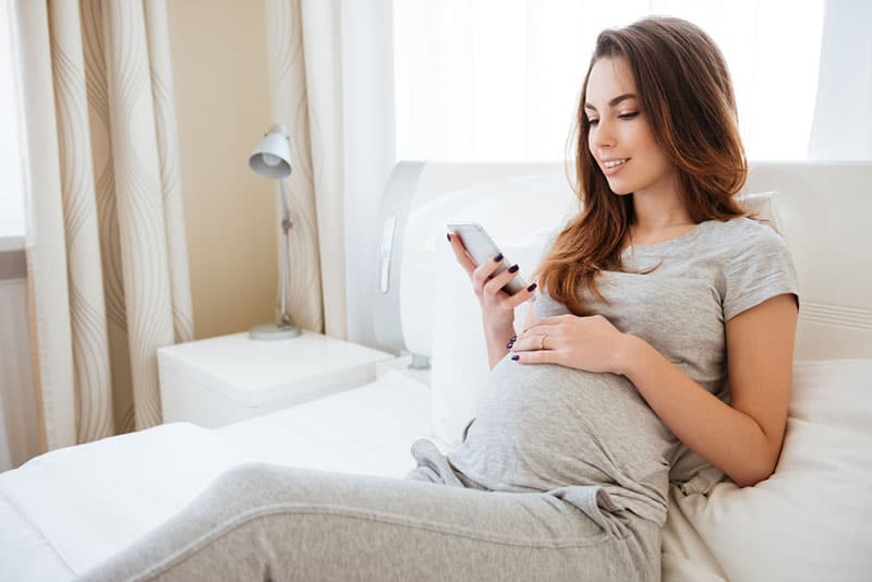 beautiful pregnant woman looking at phone