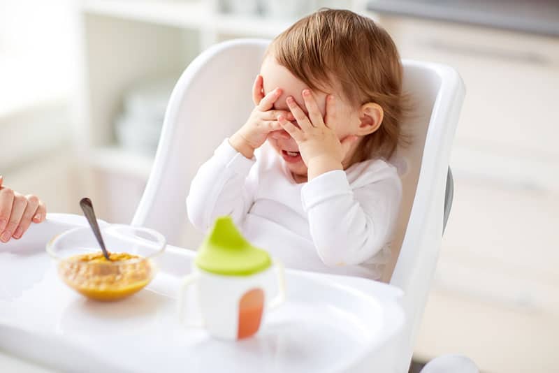 child covering eyes and refusing to eat food