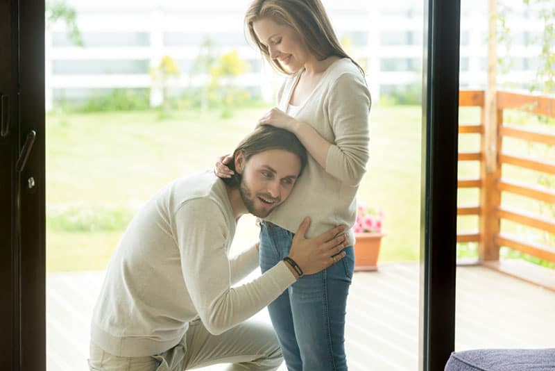 happy dad trying to feel baby moving in woman belly