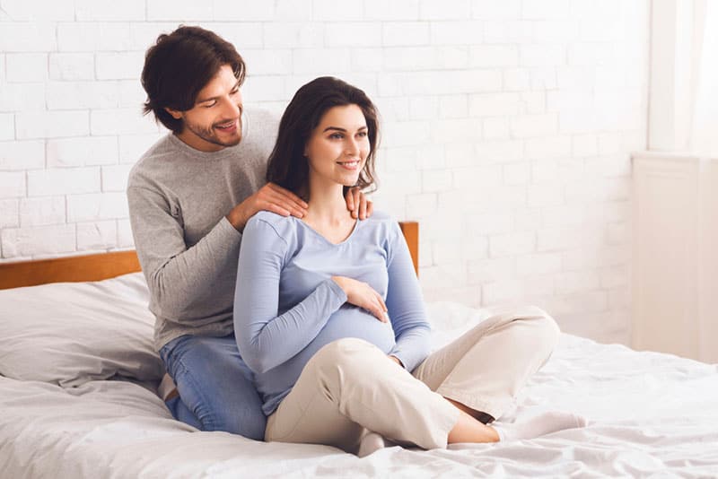 husband giving massage to pregnant wife on the bed