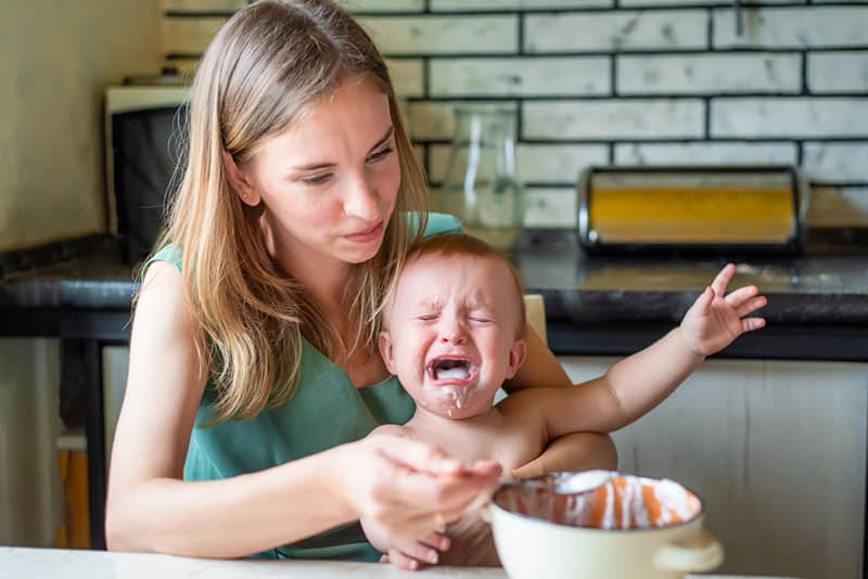 mother trying to feed crying child