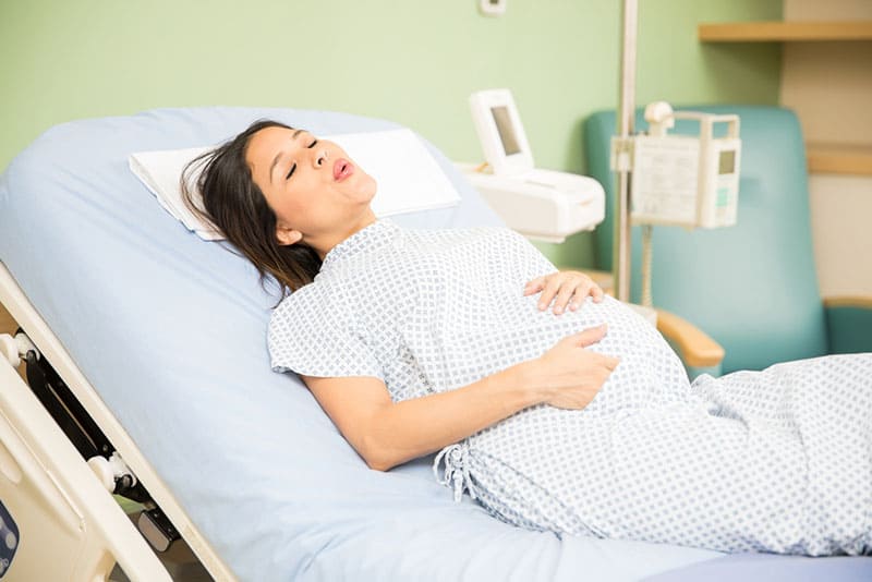 pregnant woman lying on hospital bed and having labor contractions
