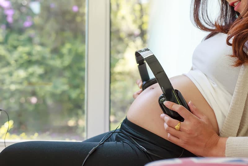 pregnant woman putting headphones for music on her belly
