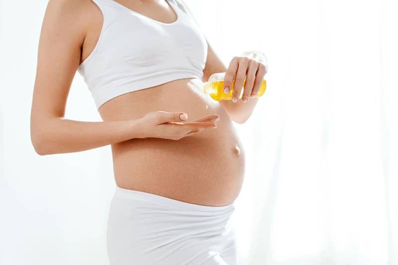 pregnant woman using essential oil for her belly
