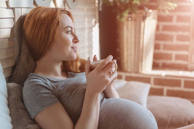 relaxed pregnant woman enjoying in cup of tea