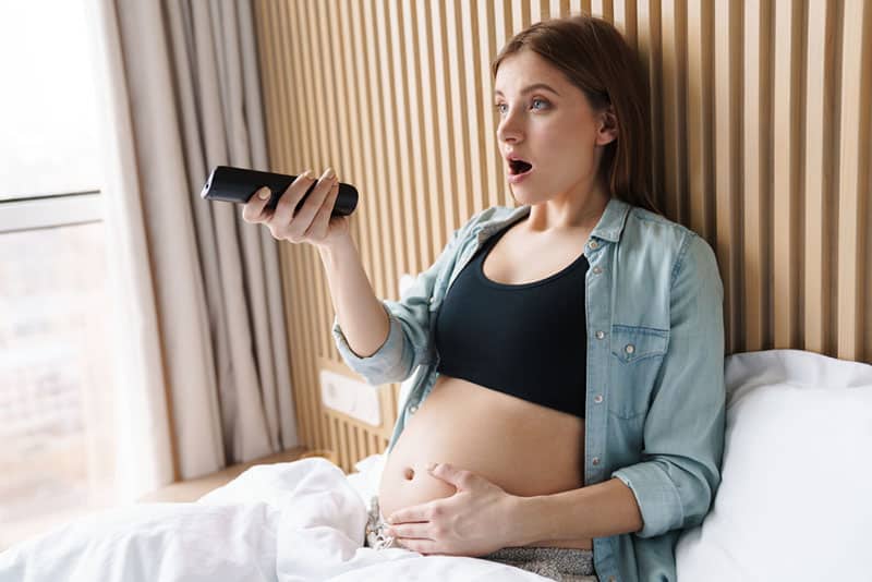 shocked pregnant woman using a remote control 