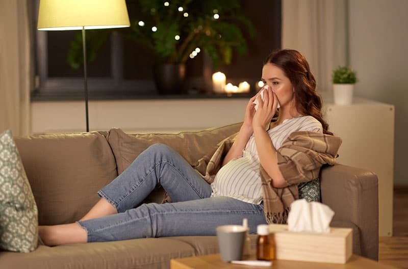 sick pregnant woman lying on the couch