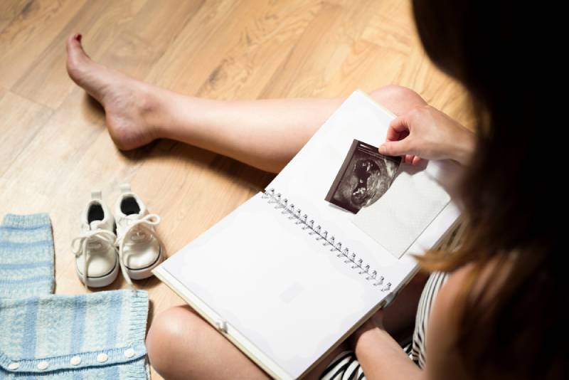 Woman placing baby's sonogram into baby's first year memory book