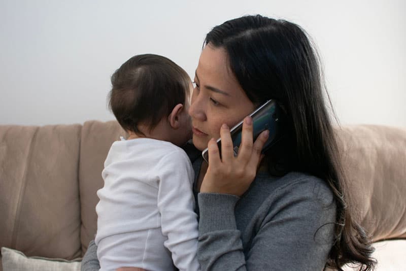 worried mother holding a baby and talking on phone