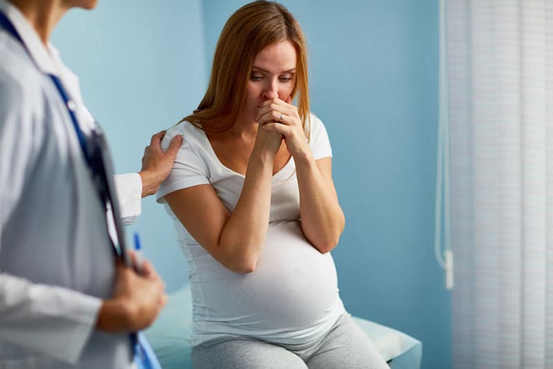 worried pregnant woman sitting with doctor