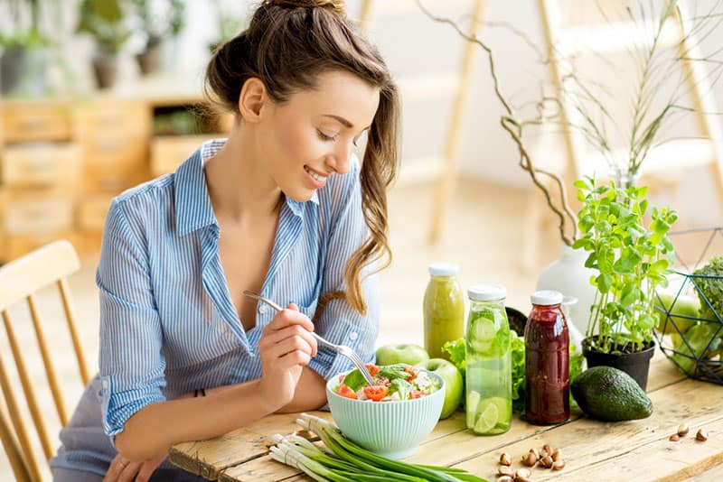 young happy woman eating vegetables