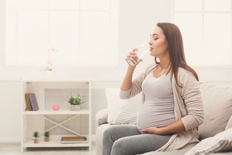 young pregnant woman drinking a glass of water