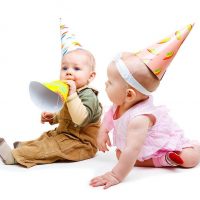 Baby boy and baby girl playing with birthday hats
