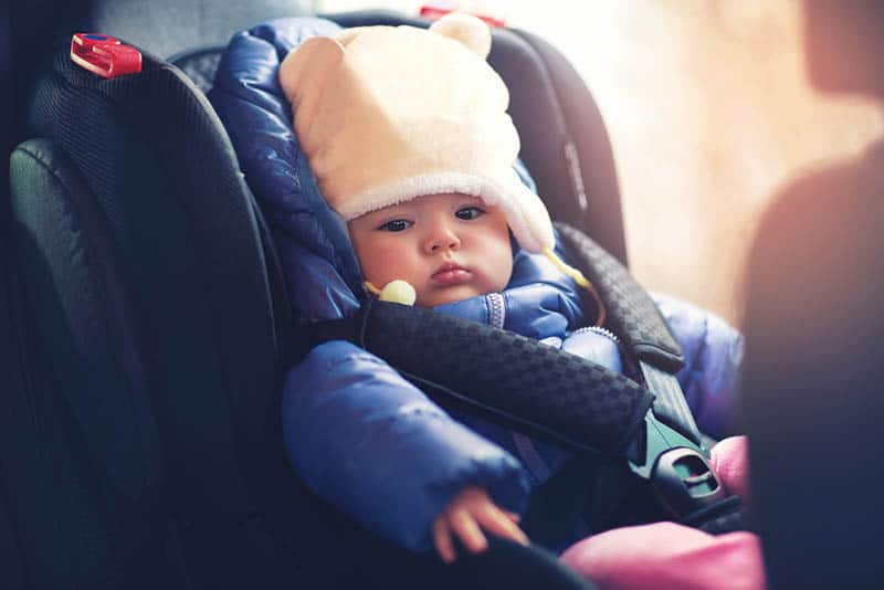 adorable baby girl in winter clothes sitting in the car seat