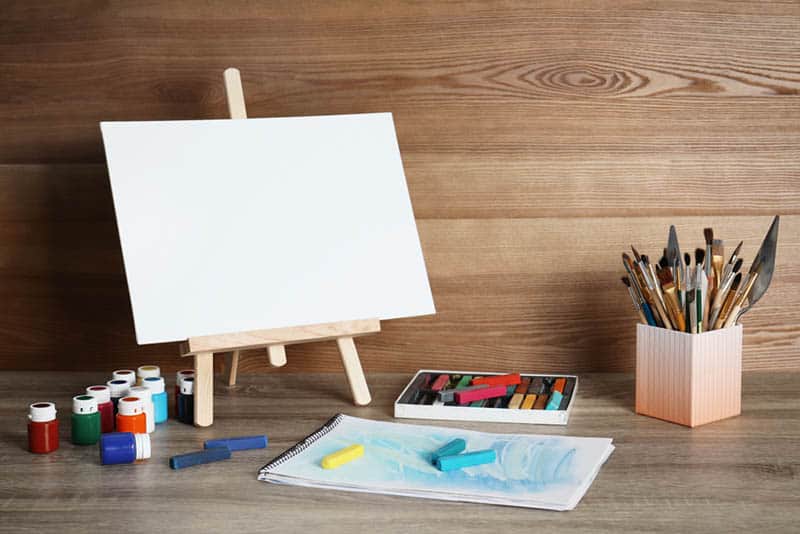 art easel with brushes and colors on the table