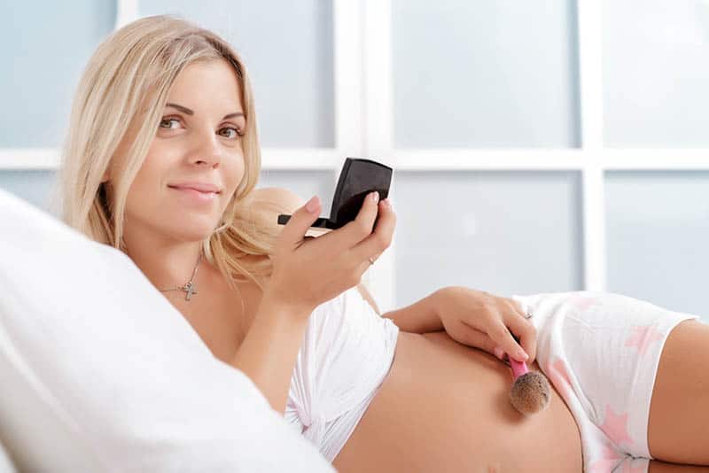 beautiful pregnant woman holding a powder and a brush