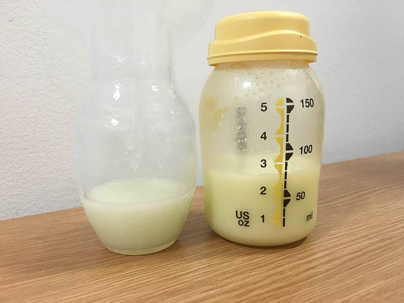 bottle of breast milk and haakaa pump breast on table