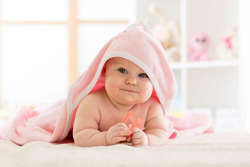 cute baby covered with pink towel after bath