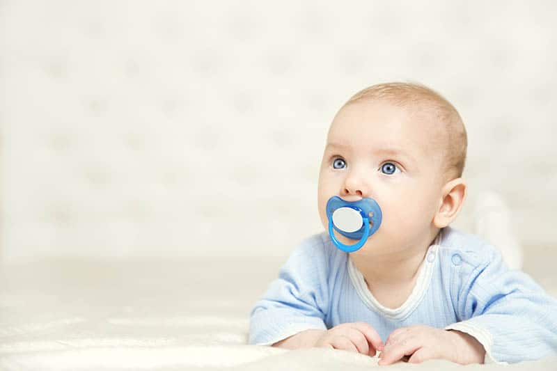 cute baby with pacifier looking at distance