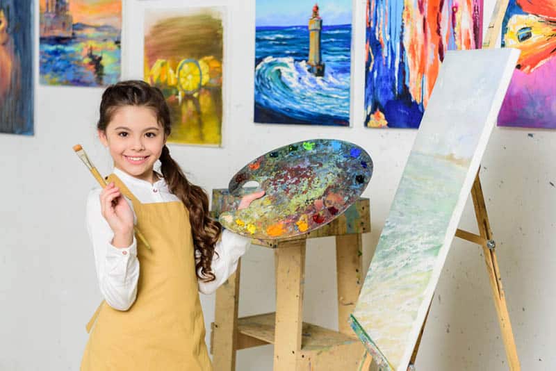 cute girl posing with painting brush and canva