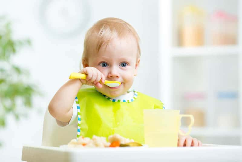 cute kid eating healthy food with spoon