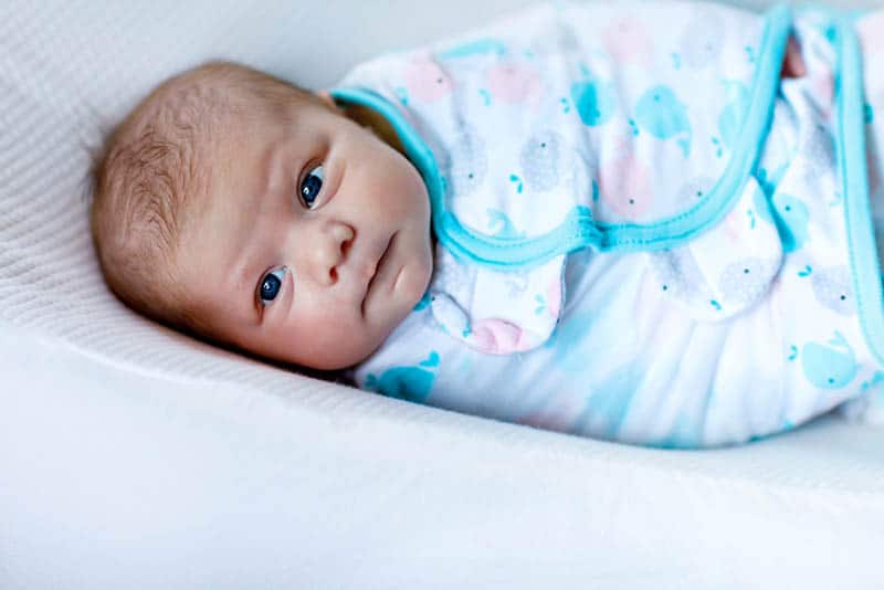 cute newborn baby wrapped into colorful blanket