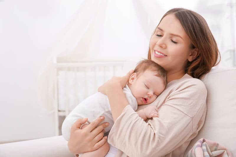 happy mother holding sleeping baby