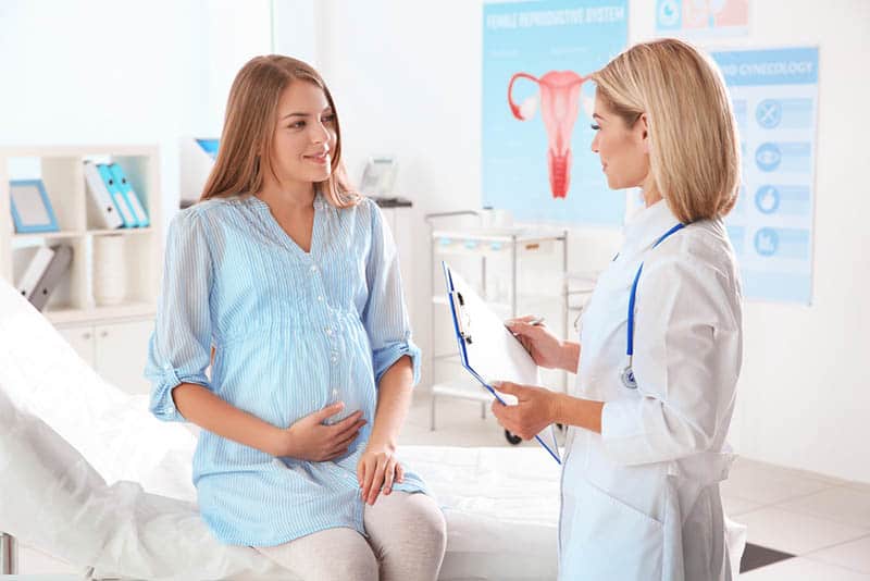 happy pregnant woman talking with doctor at hospital