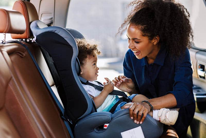 happy young mother smiling with baby in the car seat